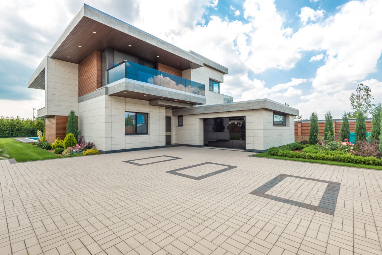 Home Elegant modern house exterior with lush greenery and ample driveway space.